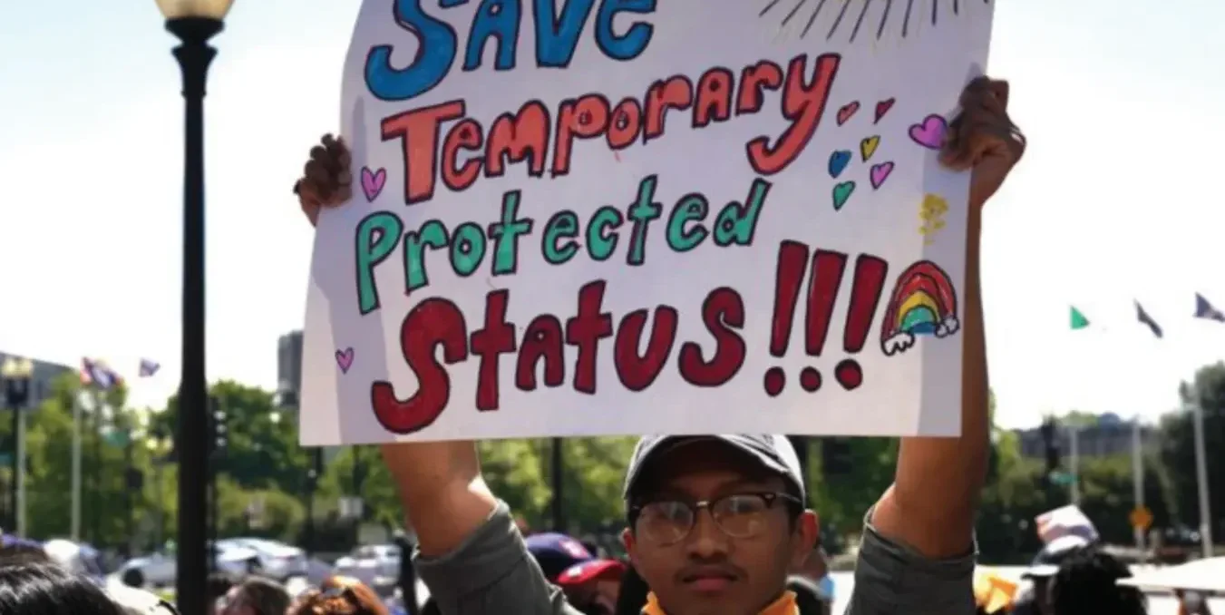 Protester holds up a home made sign that reads "Save Temporary Protected Status!!!"